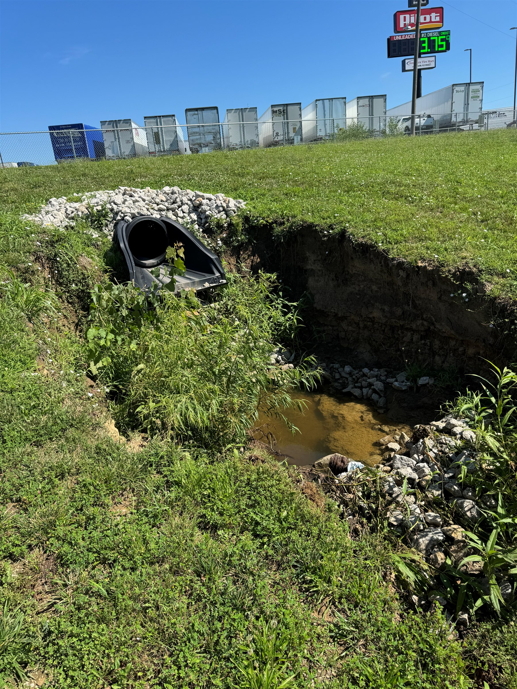 Undersized culvert outlet with active erosion scour pit before extension and stabilization